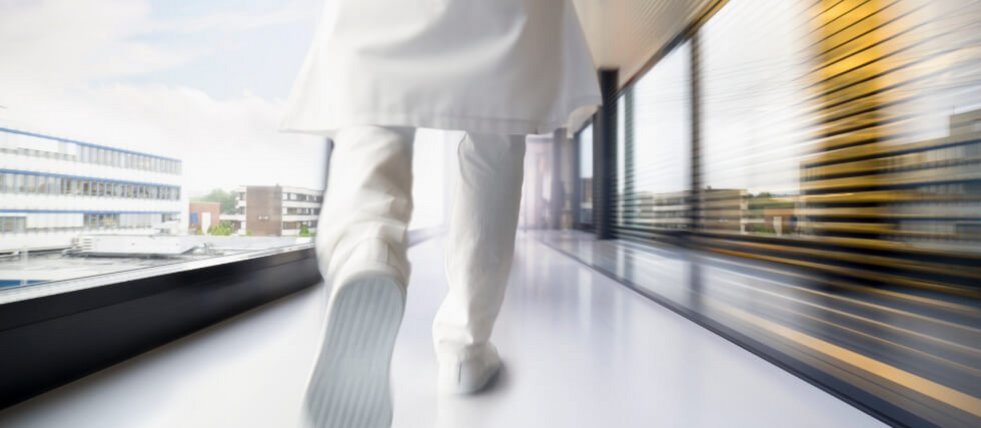 Arzt in weißer Kleidung eilt über den Krankenhausflur