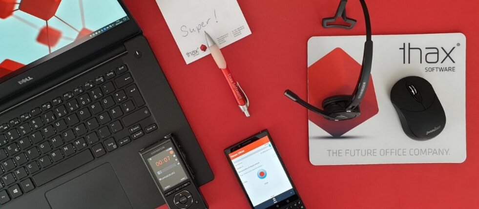 Komposition aus Laptop, Smartphone, Maus und Headset auf rotem Untergrund
