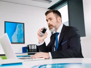 Digitales Diktieren und digitales Diktat im Berufsalltag - Ein Geschäftsmann im Büro diktiert in ein Diktiergerät